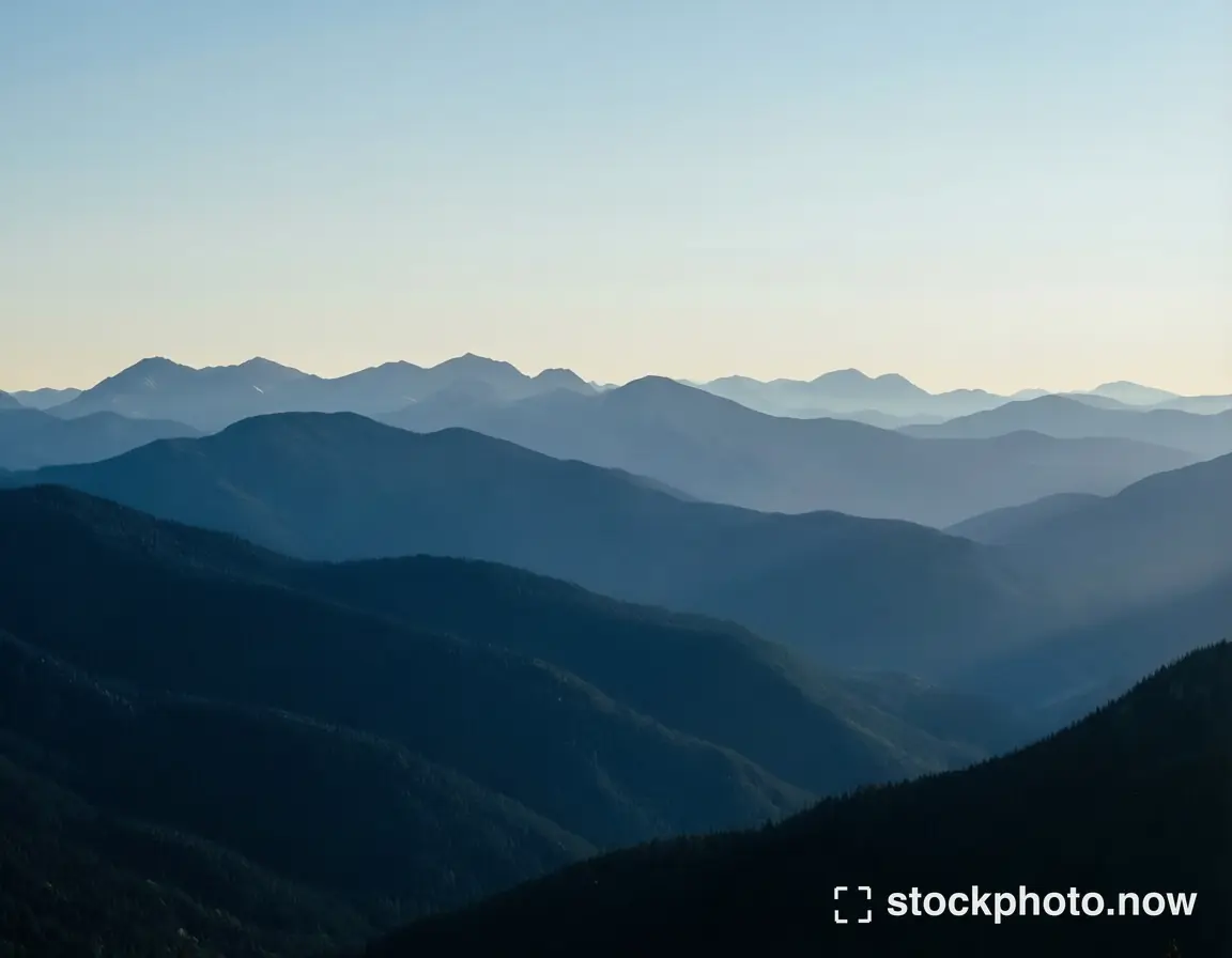 Layers of blue mountain ridges fading toward a pale clear horizon