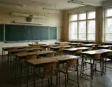 An abandoned classroom with rows of wooden desks and chairs facing a dusty chalkboard under faded fluorescent lights.