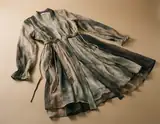 A flowing tie-dye robe with lace trim and drawstring waist lies draped on a beige surface.