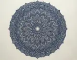 An intricate indigo circular mandala with layered floral patterns on ivory paper
