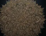 A detailed golden mandala with layered petal patterns on a black background