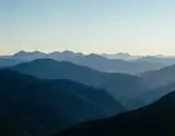 Layers of blue mountain ridges fading toward a pale clear horizon