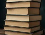 A tall stack of vintage hardcover books with worn beige pages and dark green spines stands against a deep black background.