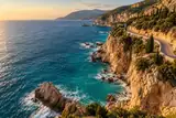 Turquoise sea beside a pale limestone coastline and a winding road