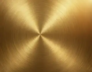 A warm gold metallic surface with fine circular brushed lines and reflected highlights