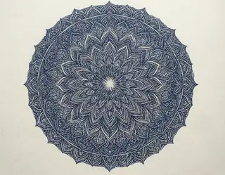 An intricate indigo circular mandala with layered floral patterns on ivory paper