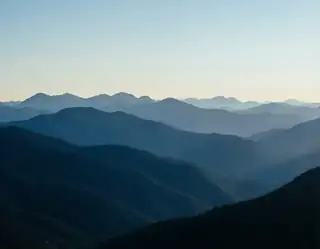 Layers of blue mountain ridges fading toward a pale clear horizon