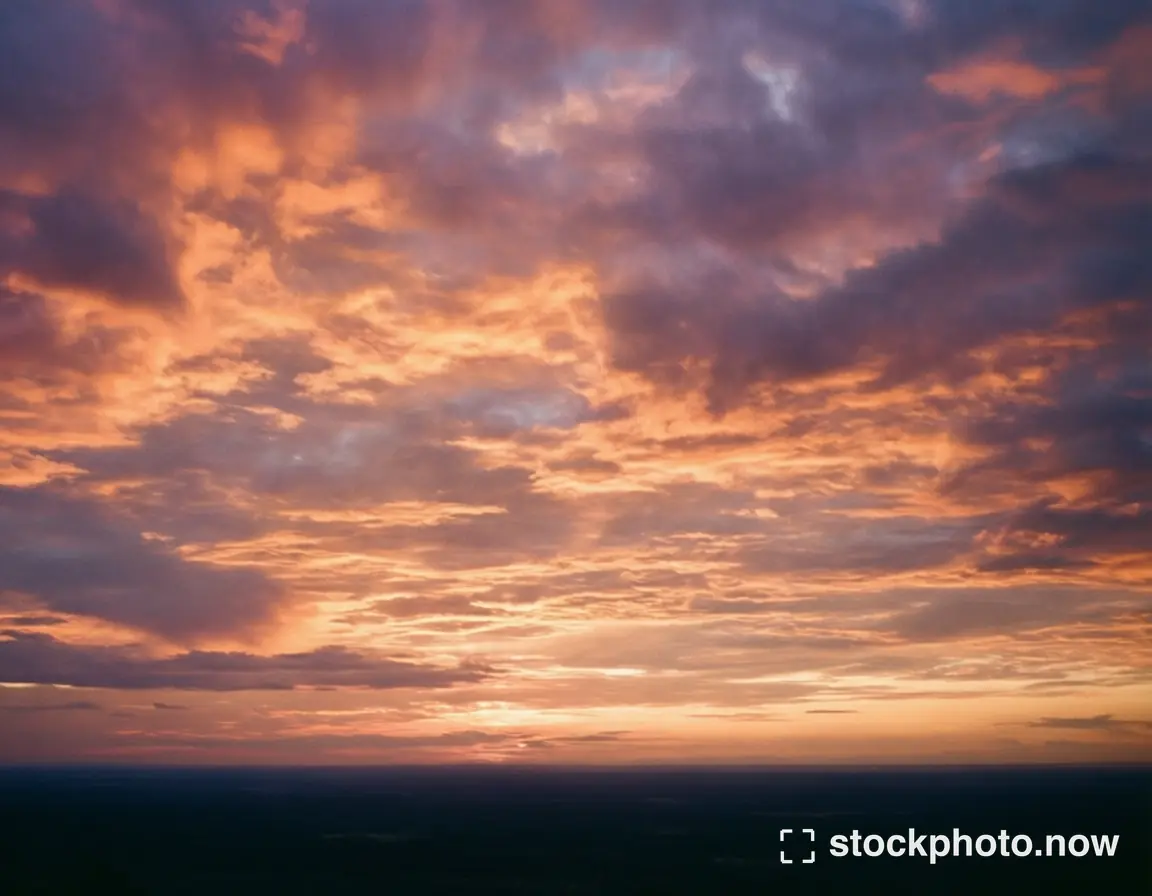 Layers of glowing peach and lavender clouds above a dark distant horizon